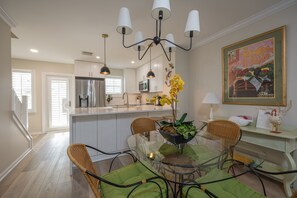 Enjoy meals in the spacious kitchen and dining area, featuring a central island, glass table, and wicker chairs.