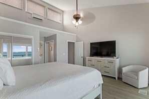 A bedroom with a large bed, a TV, a chair, and a view of the sea. - SEAS THE DAY, Your Happy Place! 208- Destin Seafarer (Destin)