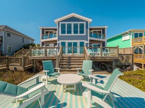 Enjoy the ocean views from the spacious balcony with comfortable seating and a wooden staircase.