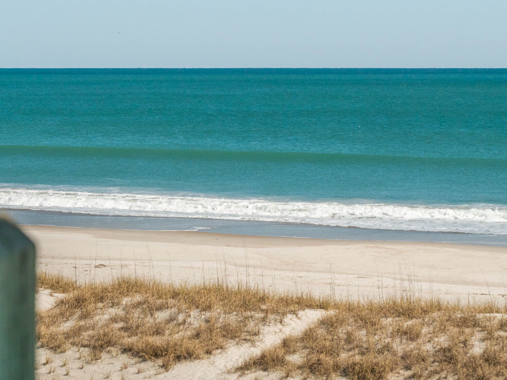 A beach with clear blue water and a sandy shore.