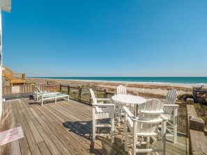 A wooden deck with white chairs and a table overlooking a beach. - Beach Coma | Oceanfront, Hot Tub on the Deck! (Topsail Beach)