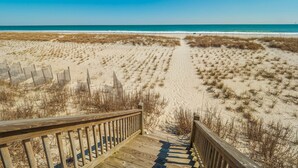 A wooden staircase leading down to a sandy beach with dunes and a clear blue sky. - Beach Coma | Oceanfront, Hot Tub on the Deck! (Topsail Beach)