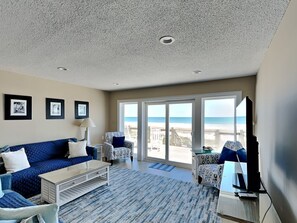 Relax in this inviting living room with a sofa, coffee table, and balcony overlooking the ocean.