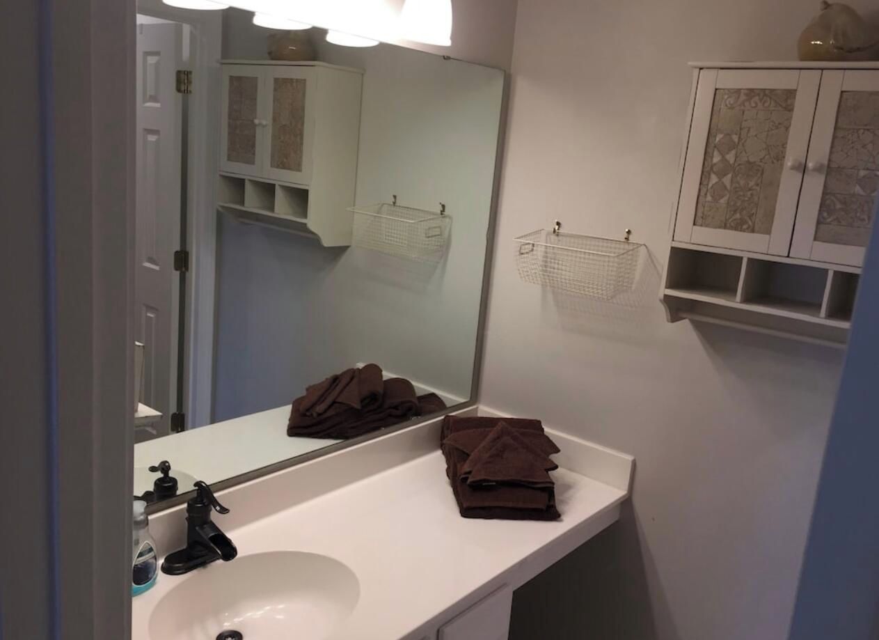 A bathroom with a white sink, a mirror, and a towel rack.