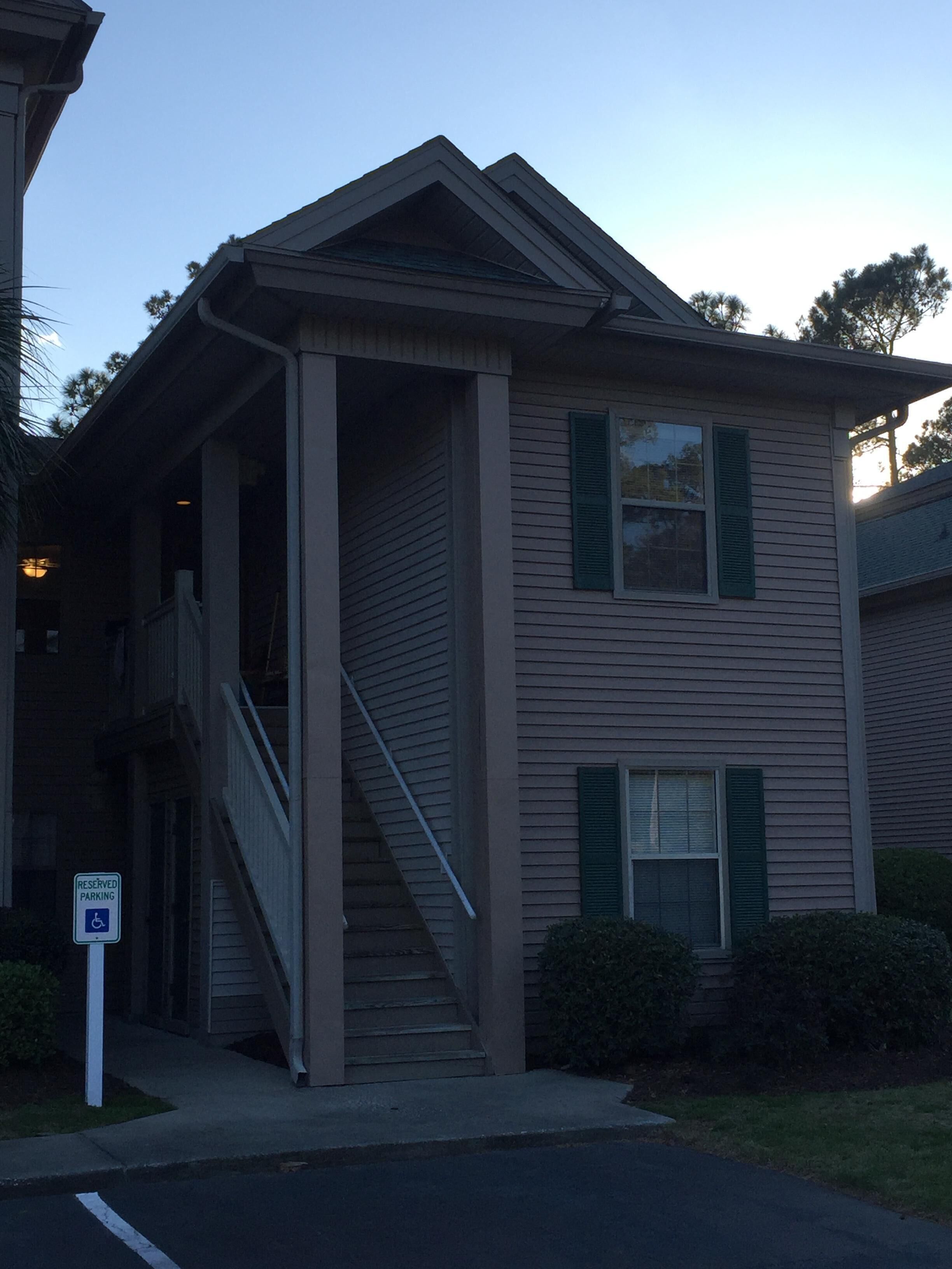 A two-story building with a covered front porch and a staircase leading to the entrance.