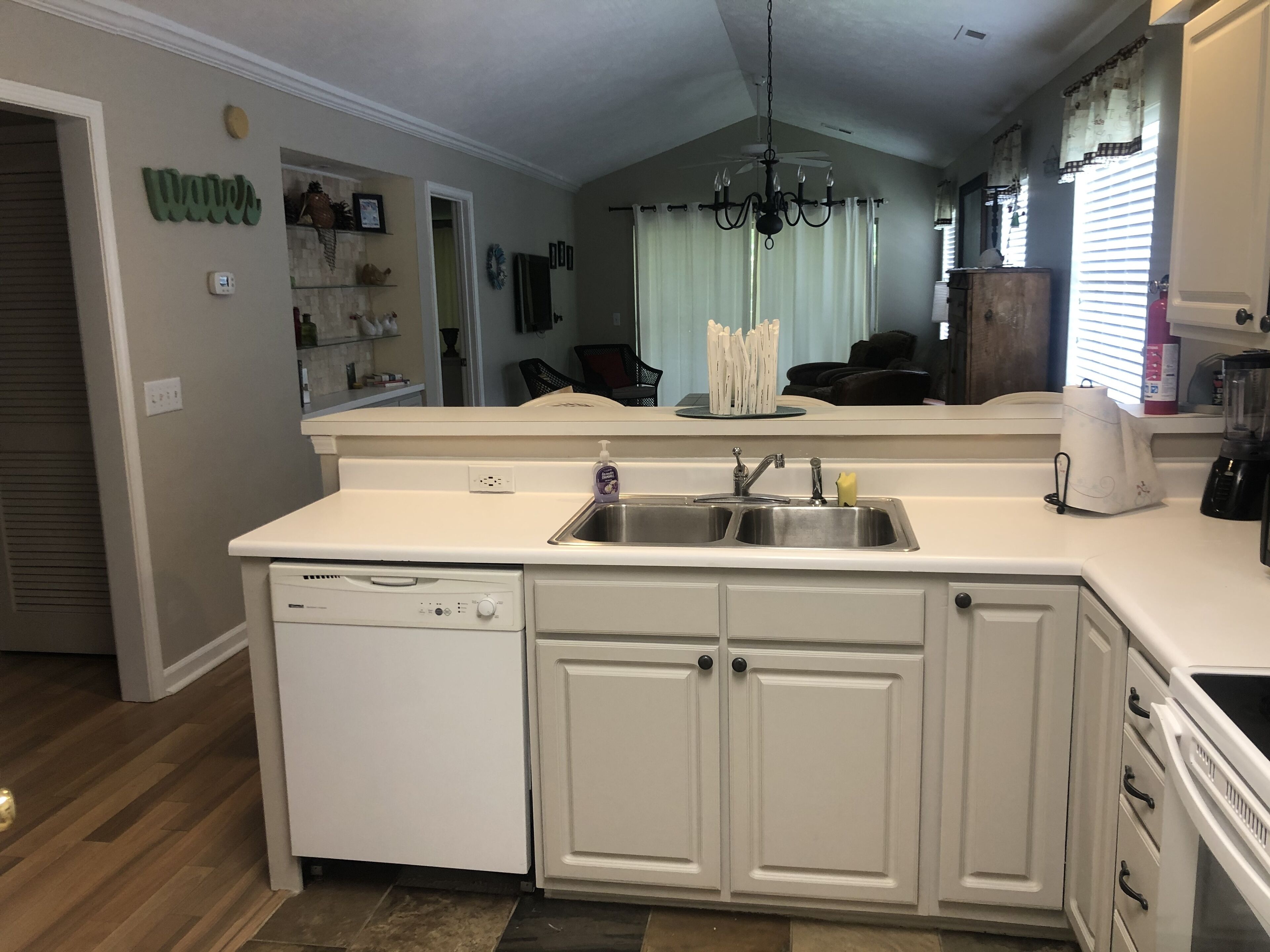 A kitchen with white cabinetry, a dishwasher, a double sink, and a ceiling fan.