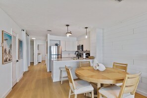 A modern kitchen with white cabinetry, a central island, and pendant lighting.