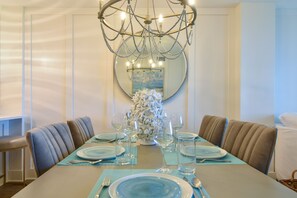 Enjoy meals in this dining area with a long table, comfortable chairs, and a large mirror above.