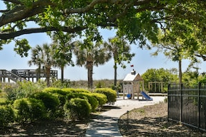 A park with a playground, a wooden bridge, and a gazebo.