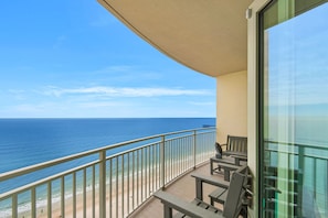 Uma varanda com vista para o oceano, um banco e uma mesa.
