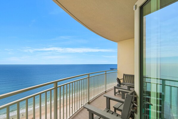 A balcony with a view of the ocean, a bench, and a table.