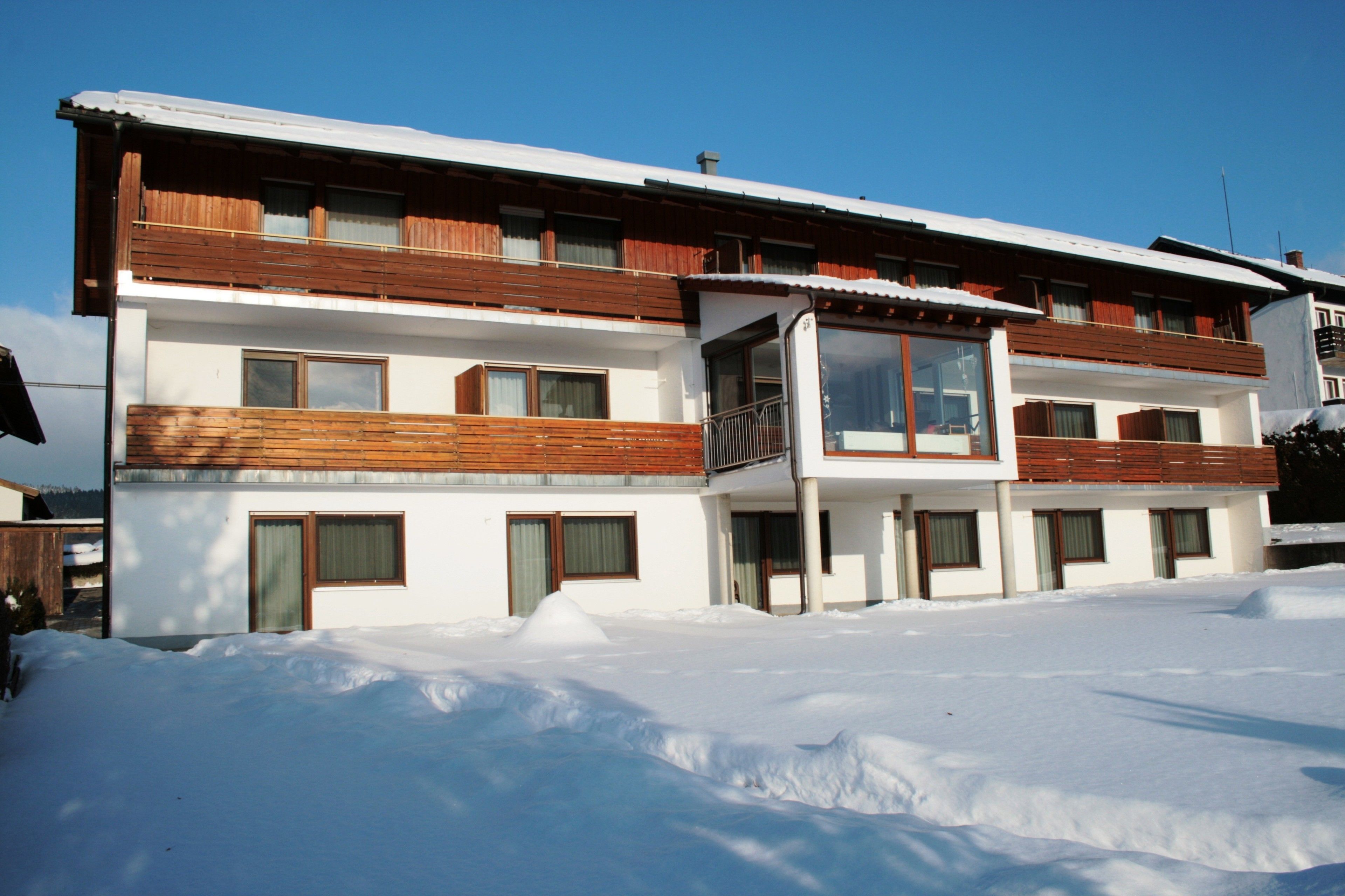 A two-story building with wooden balconies and large windows.
