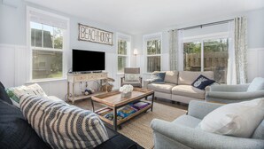 A living room with a television, sofas, a coffee table, and a bookshelf. - Hot tub, EV friendly, main floor primary suite with plenty of space. (South Haven)