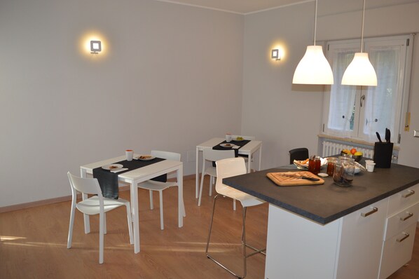 A modern kitchen with white cabinetry, a central island with a cutting board, and two pendant lights.