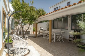 A patio with outdoor furniture, a hanging chair, and a covered area with a table and chairs.