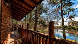 Eine Holzterrasse mit Geländer, mit Blick auf einen See und einen Wald.