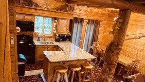 Ein Interieur einer Holzhütte mit einer Küchenzeile, die eine Granitabdeckung, Holzstühle und einen Esstisch zeigt.
