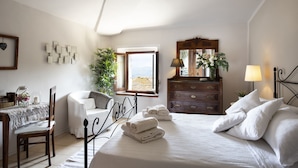A bedroom with a bed, bedside table, chair, dresser, and a window with a view. - The Gelda house, relax with a view (Castelnuovo dell'Abate)