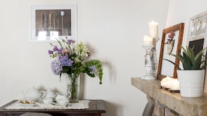 A dining area with a wooden table, two chairs, a vase with flowers, a candle holder, and a fireplace. - The Gelda house, relax with a view (Castelnuovo dell'Abate)