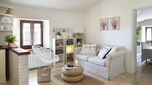 A modern living room with a white sofa, a white chair, a small round table, and a bookshelf. - The Gelda house, relax with a view (Castelnuovo dell'Abate)