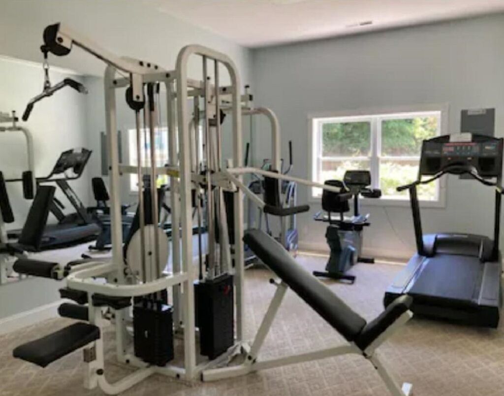 A gym with various exercise equipment including a bench press, a treadmill, and weight machines.