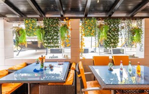 An outdoor seating area with glass tables and wicker chairs, decorated with hanging floral arrangements and a 'relax' sign. - Amazing home in Banjole with sauna (Banjole)