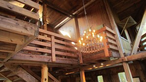 Ein Holzinnenraum mit einer Chandelüstere, Holzbalken und einer Treppe.
