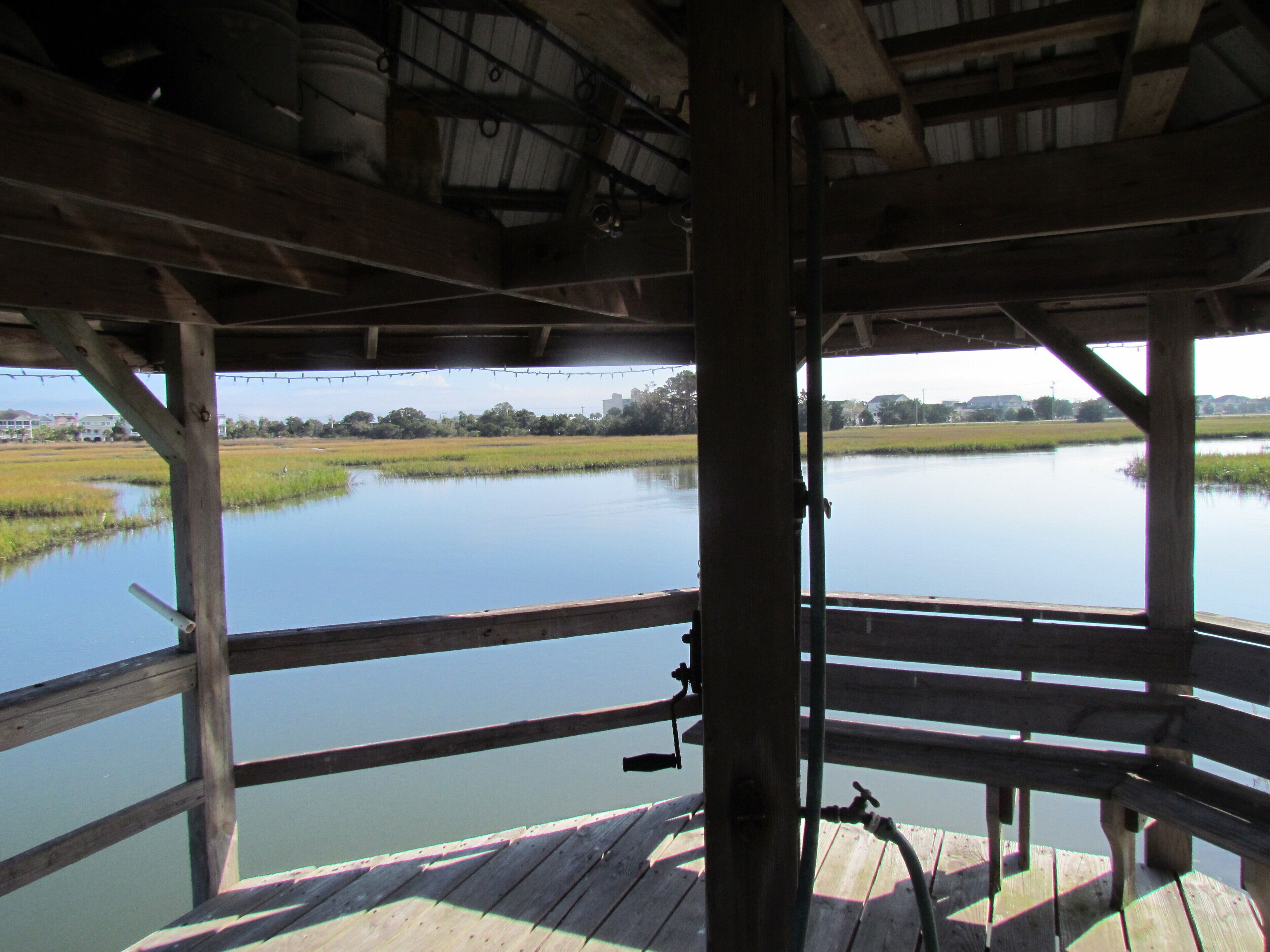 A wooden deck with a view of a calm water body and distant buildings.