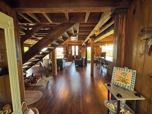 A spacious wooden interior with a staircase, seating area, and a bar. - Cozy Creek Front Retreat (Pawleys Island)