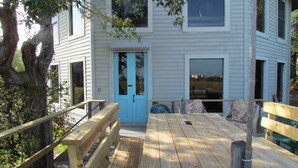 Eine Holzterrasse mit einer blauen Tür, die zu einem Gebäude mit großen Fenstern führt.