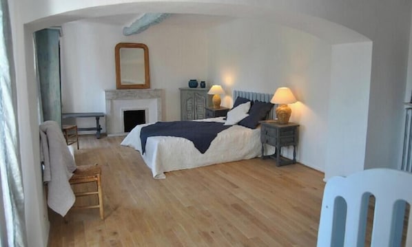 A bedroom with a bed, two bedside tables with lamps, a chair, a fireplace, and a mirror on the wall. - Superb Provençal bastide in Mouans-sartoux: 10 people (Mouans-Sartoux)