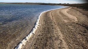 A beach with clear water and a sandy shore.