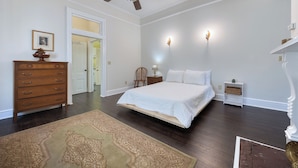 Een slaapkamer met een bed, dressoir, nachtkastje en een plafondventilator.