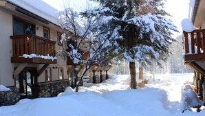 Ein schneebedecktes Gebäude mit einem hölzernen Balkon und einem Steinfundament.