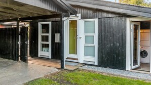 A small, single-story building with a dark exterior, white-framed windows, and a covered porch area. - Pet friendly home in Væggerløse with WiFi (Væggerløse)