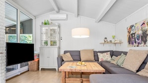 A modern living room with a grey sofa, a wooden coffee table, and a TV on a white brick wall. - Pet friendly home in Væggerløse with WiFi (Væggerløse)