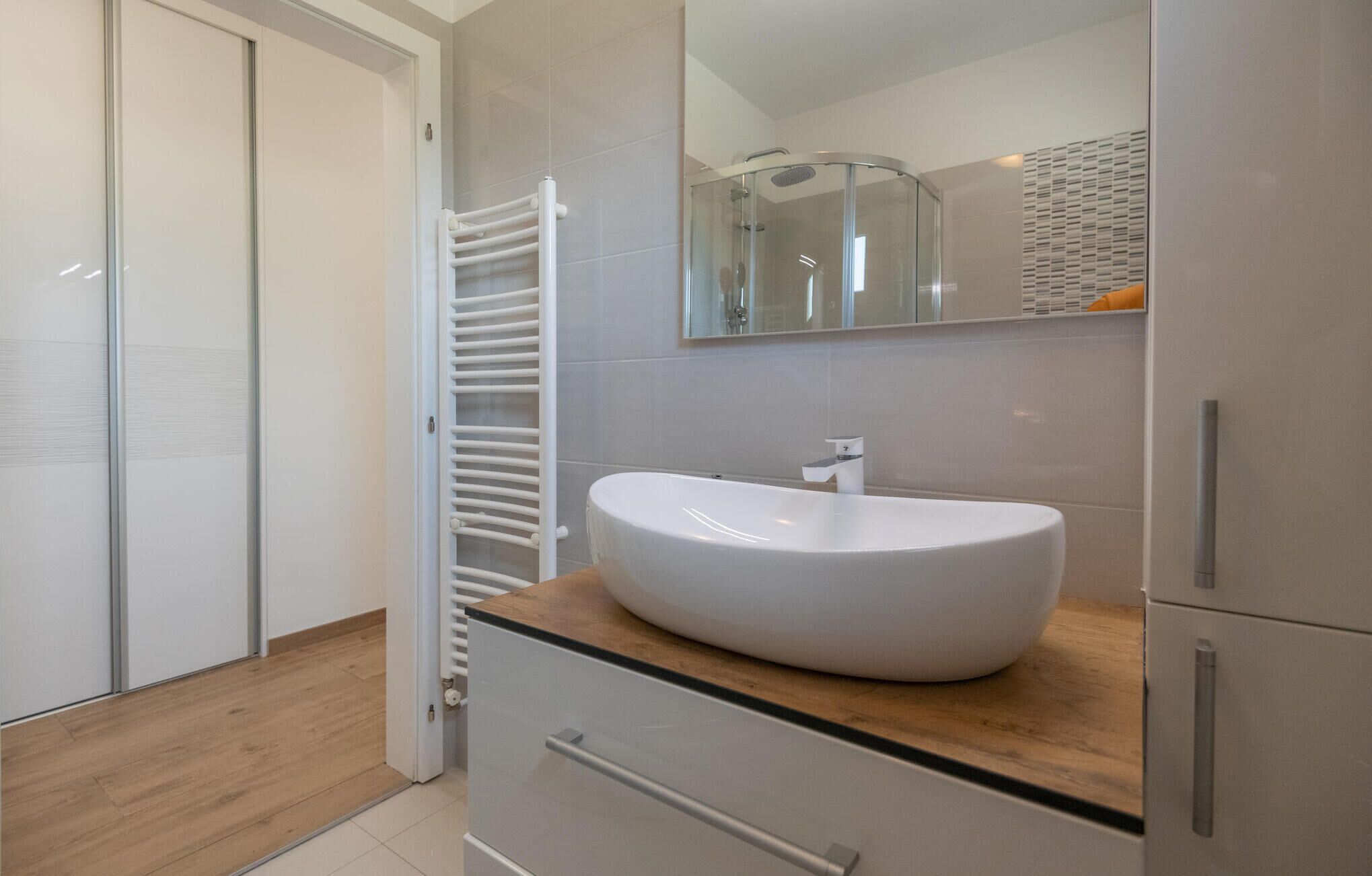 A modern bathroom with a white sink, wooden countertop, and a glass shower enclosure.