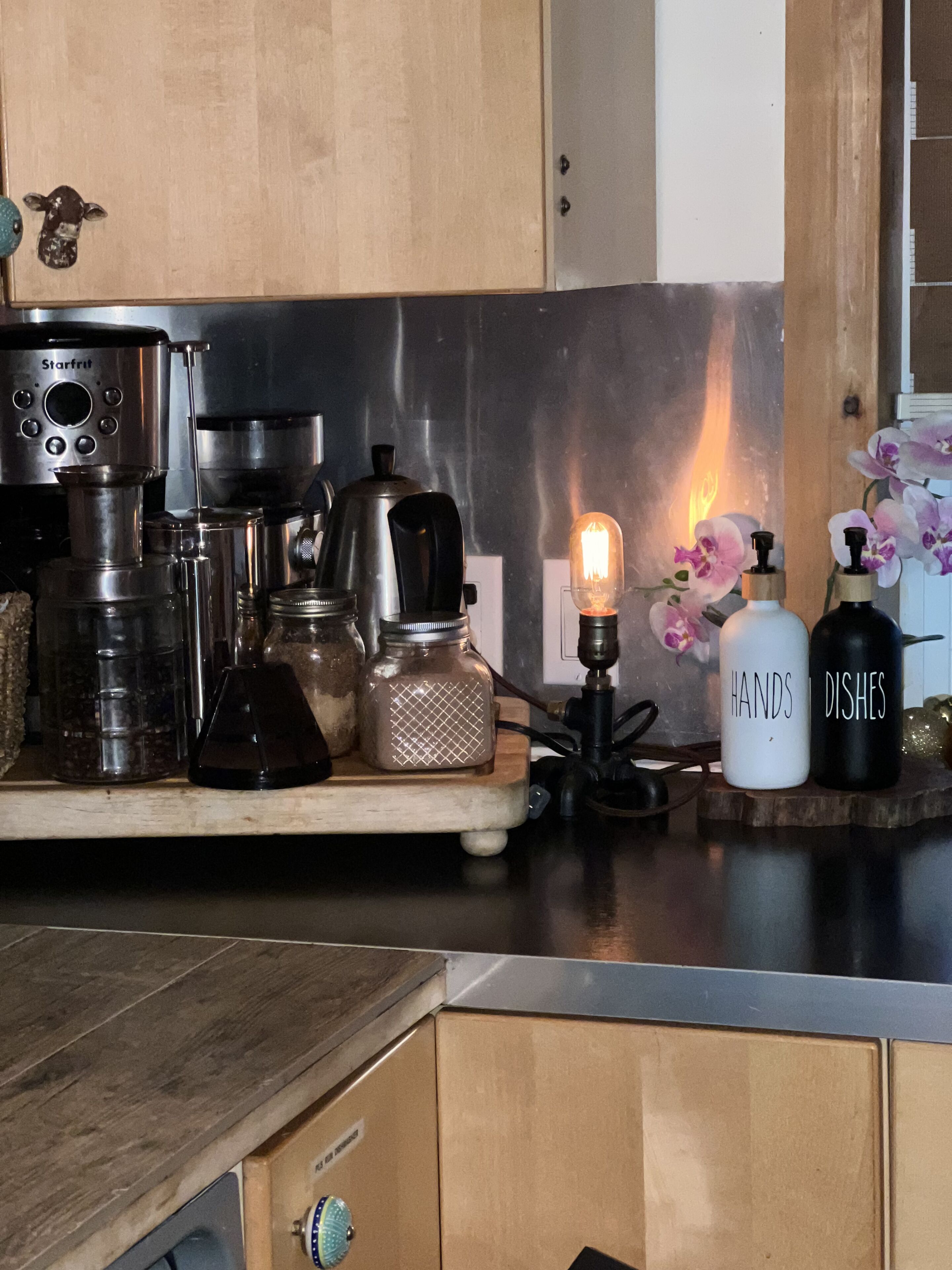 En köksbänk med kaffebryggare och tillbehör, burkar och dekorativa föremål.