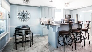 A kitchen with a central island, bar stools, and a dining table.