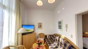 Una sala de estar con un sofá, un televisor y una lámpara.
