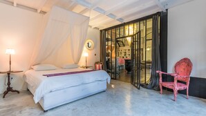 Une chambre à coucher avec un lit, des lampes de chevet, une chaise et une porte vitrée donnant sur un escalier.