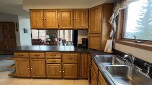 Una cocina con armarios de madera, encimera de granito, estufa integrada y un ventanal grande.