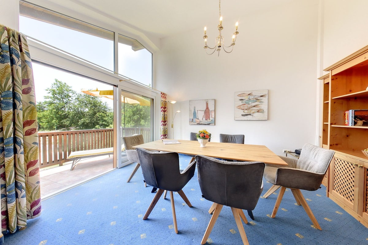 A dining area with a large table, black chairs, and a blue carpet.