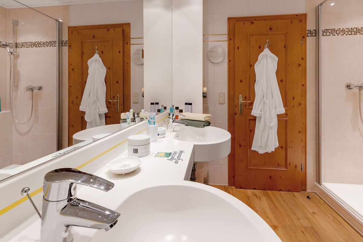 A bathroom with a large mirror, a bathtub, a sink, and two shower stalls.