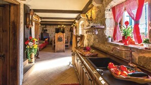 A rustic kitchen with stone walls, wooden beams, and a stone fireplace. - Amazing home in Podgora with sauna (Podgora)