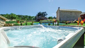 A hot tub with a stone building in the background. - Amazing home in Podgora with sauna (Podgora)