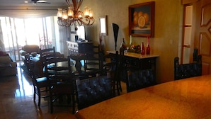 A dining area with a large table and chairs, a chandelier, and a painting on the wall.