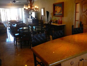 A dining area with a large table and chairs, a chandelier, and a painting on the wall. - 7th Floor Ocean View in Highly-Rated Villa La Estancia Resort (Cabo San Lucas)