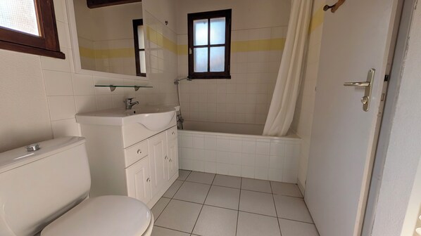 A bathroom with a toilet, sink, and bathtub.