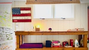 Un banc en bois doté d’étagères de rangement, une petite table avec une lampe et un élément décoratif mural.